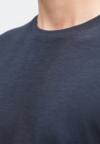 Tumši zils T-krekls ar apaļu izgriezumu, izgatavots no teksturētas, vieglas auduma ar īsām, mīkstām piedurknēm un gludu kakla izgriezumu.