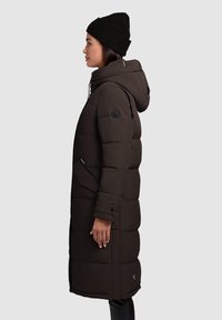 Mørk, isoleret lang jakke med kviltet design, hætte og sidelommer. Har et sort logo-patch på ærmet og struktureret stof.