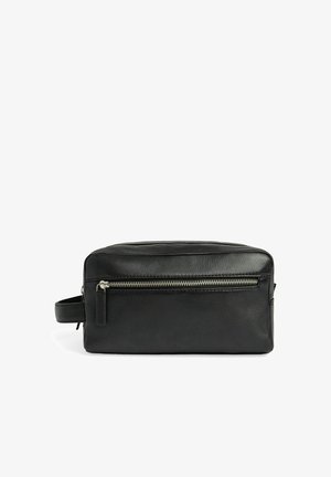 Trousse de toilette en cuir noir avec fermeture éclair sur le dessus et poche zippée à l'avant, avec poignée latérale.
