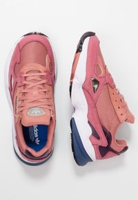 Sneaker in suede rosa e rete con design a lacci, suola intermedia bianca e suola in gomma nera con accenti viola.