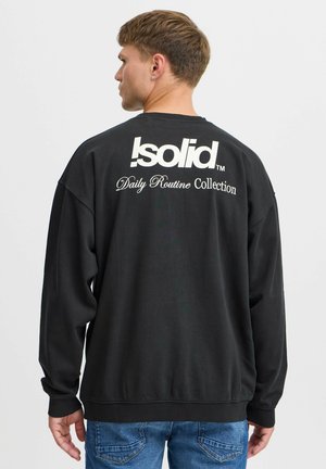 Black sweatshirt with a relaxed fit, featuring a large white logo and text on the back. Ribbed cuffs and hem, soft texture, casual design.