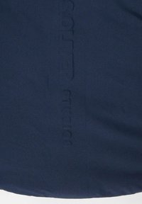 Navy textiel met een subtiele, gestructureerde oppervlakte. Kenmerkt zich door geperst merklogo aan één zijde, waarbij het materiaal en ontwerp worden benadrukt zonder versieringen.