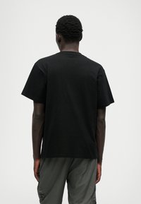 T-shirt preta de algodão com decote redondo e mangas curtas, apresentando um corte descontraído. Vista pela parte de trás, sem padrões ou detalhes distintos.