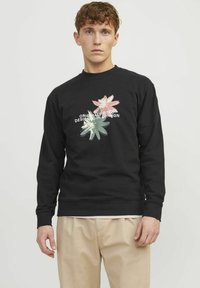 Sudadera negra con un gráfico floral en rosa y verde, y el texto "ORIGINALS ©1990 DISEÑADO EN COPENHAGUE" en el frente. Material de algodón.