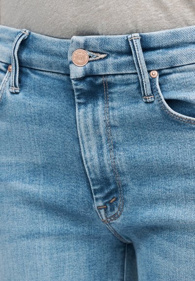 Ανοιχτό μπλε τζιν με ομαλή υφή, διαθέτει χαλκό κουμπί, διακριτικές ραφές και τυπικές μπροστινές τσέπες.