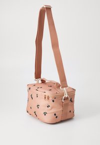 Borsa di stoffa color pesca con una superficie liscia, dotata di chiusura con zip e motivi di bacche nere, fornita di una tracolla regolabile.