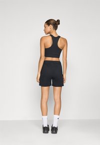 Svart atletisk cropped topp och shorts med racerback-design. Tyget verkar slätt med elastisk midja och sidofickor.