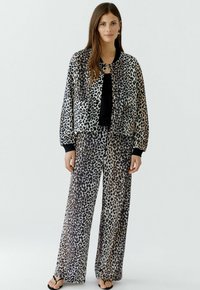 Leoprint Bomberjacke mit passenden weit geschnittenen Hosen, versehen mit schwarzem Saum und weichem, leichtem Stoff. Beide Teile haben eine oversized Passform.