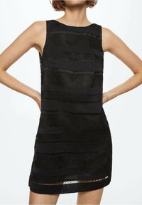 Robe noire sans manches avec des rayures horizontales texturées et une finition en tissu lisse. Présente une coupe droite et une longueur au-dessus du genou.