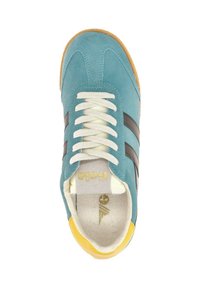 Zapatilla azul de ante con rayas marrones, cordones blancos y un acento amarillo en el talón. Textura suave y diseño de punta redondeada. Logotipo de la marca visible.