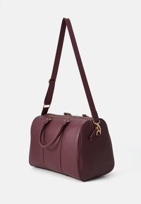 Burgundy leather duffel bag with double handles and a detachable shoulder strap, featuring gold hardware and a rounded shape.