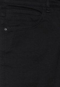 Jeans de mezclilla negra con un diseño de corteSlim, que incluyen un bolsillo frontal, detalles de costura sutiles y un botón de metal en la cintura.
