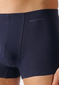 Boxers en coton bleu marine avec une texture lisse. Présentent une couleur unie, une taille élastique avec logo, et un design de poche profilé.