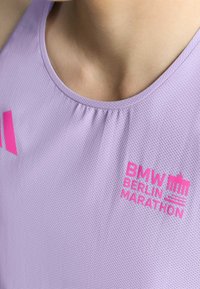 Svijetlo ljubičasti atletski majica bez rukava s teksturiranim materijalom. Ružičasti logo s natpisom "BMW BERLIN MARATHON" s ikonim znamenitosti.