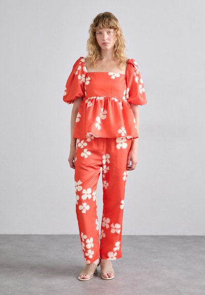 Red floral two-piece outfit featuring a square neckline top with puffed sleeves and loose-fitting pants with white flower patterns.