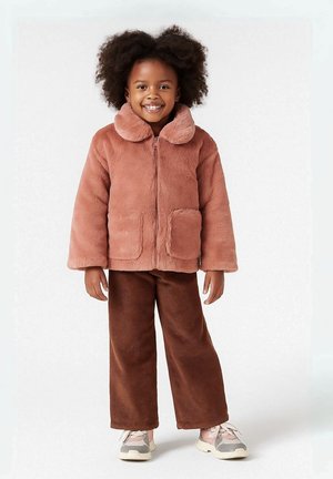 Lichte roze nepbont jas met een ronde kraag, een ritssluiting aan de voorkant en twee opgestikte zakken, gecombineerd met een bruine corduroy broek met brede pijpen.