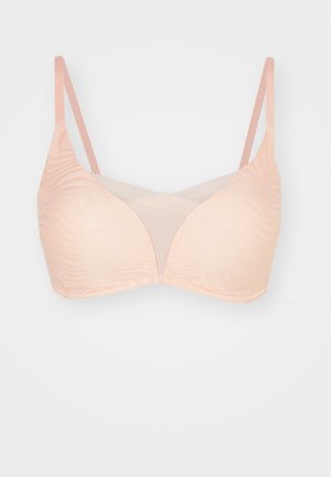 Peach-colored bra with smooth, wavy texture, mesh panels, and adjustable straps. Features a triangular cup design.