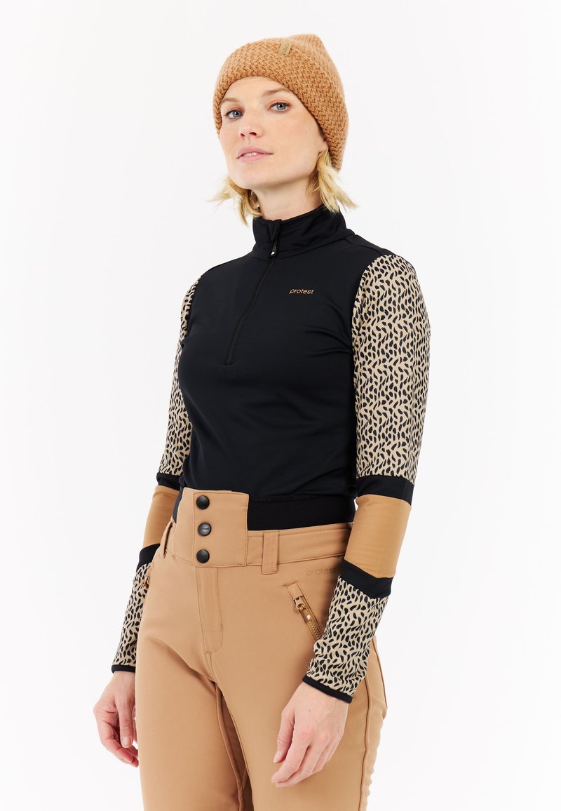 Zwarte zip-up top met mouwen van luipaardprint, bruine accenten en een hoge kraag, gecombineerd met tan broek met drie knopen en een ritszak.