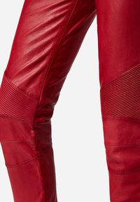 Rode leren broek met een gladde textuur, ribbelaccenten en naaddetails, die een aansluitend ontwerp en taps toelopende vorm toont.