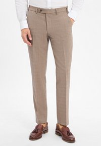 Beige karierte Hose mit schlanker Passform, mit Knopfverschluss, seitlichen Taschen und einer glatten Stofftextur. Kombiniert mit braunen Mokassins.