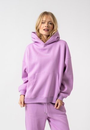 Felpa con cappuccio viola realizzata in tessuto morbido, dotata di una tasca frontale e vestibilità comoda. Logo di piccole dimensioni sul petto. Abbinata a pantaloni coordinati.
