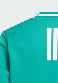 Jersey deportivo color turquesa con franjas blancas en el cuello y tres franjas verticales blancas en la parte posterior, fabricado con un tejido de textura suave.