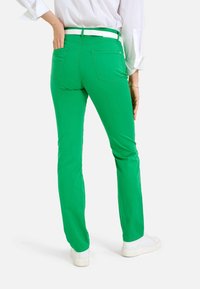 Pantalons en coton verts à coupe slim, avec poches arrière, taille mi-haute et une ceinture blanche. Texture lisse, design à jambes droites.