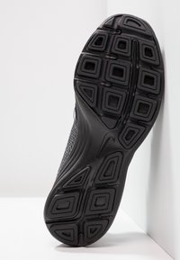 Sole di scarpa da ginnastica nera con superficie in gomma testurizzata, caratterizzata da un motivo geometrico di quadrati e rettangoli per trazione e supporto.