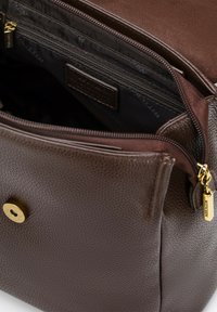 Sac en cuir marron avec une texture en relief. L'intérieur comporte une poche zippée et un revêtement en tissu. Le matériel en or accentue le design.
