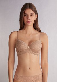 Tan kanten beha met beugel, voorzien van een scalloped rand en een decoratieve strik in het midden. Verstelbare bandjes, gladde textuur, motief van kant.