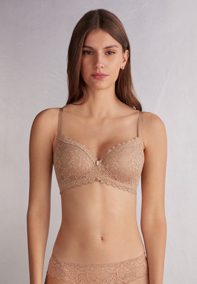 Tan kanten beha met beugel, voorzien van een scalloped rand en een decoratieve strik in het midden. Verstelbare bandjes, gladde textuur, motief van kant.