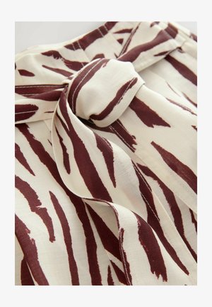 Een stof met een crèmekleurige basis met kastanjebruine abstracte strepen. Het materiaal is zacht en lichtgewicht, met een strikaccent voor sluiting.