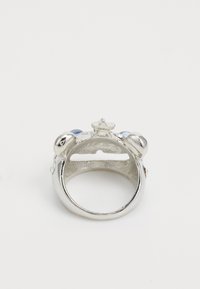 Anillo de plata con un acento en forma de estrella y dos piedras azules. Superficie de metal lisa con un acabado pulido. El interior presenta un patrón texturizado.