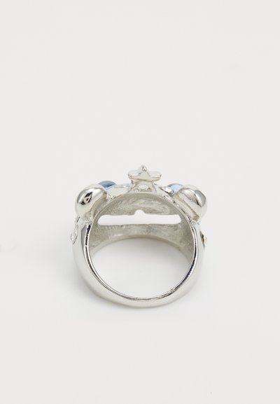 Bague en argent mettant en avant un accent en forme d'étoile et deux pierres bleues. Surface métallique lisse avec une finition polie. L'intérieur présente un motif texturé.