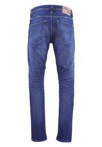Jean en denim bleu coupe slim. Comprend deux poches arrière, une étiquette en cuir sur la ceinture, et des coutures jaunes le long des coutures.
