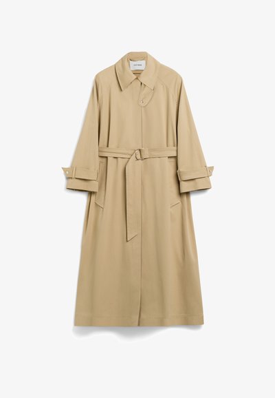 Beżowy trencz z gładkiego materiału, z paskiem w talii, kołnierzem typu lapel i dużymi kieszeniami bocznymi. Rękawy wywinięte z zapięciem na napy.