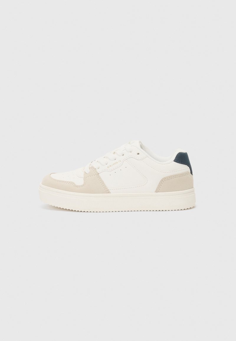 Baskets basses blanches avec des accents beige, fermeture à lacets à l'avant et languette de talon foncée, présentées sur un fond gris clair.