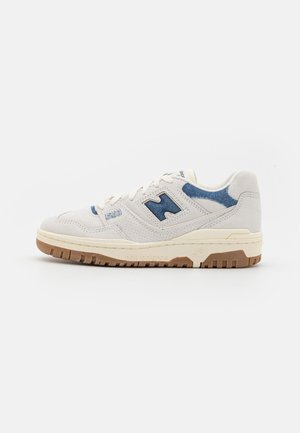 Hellbeiger New Balance 550 Sneaker mit blauen Akzenten, perforiertem Obermaterial aus Wildleder und Gummisohle, im Seitenprofil dargestellt.