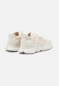 Sneaker bianche chunky con accenti testurizzati; tomaia in rete con motivo ondulato crema e marchio sul tallone; suola imbottita.