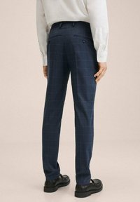 Námořnické kárované kalhoty s úzkým střihem, hladkou látkou, dvěma zadními kapsami a decentním kostkovaným vzorem, doplněné černými botami.