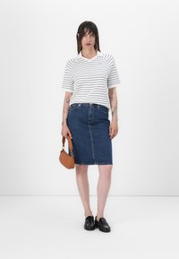 Stripet hvit T-skjorte med korte ermer, kombinert med et blått denim blyantskjørt. Tilbehør inkluderer en liten brun håndveske og svarte sko.