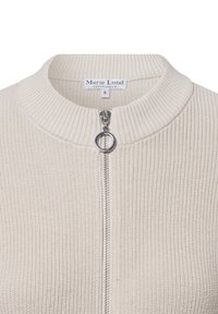 Cremfarbener Ripp-Pullover mit hohem Kragen, Frontreißverschluss und silbernen Beschlägen. Beinhaltet ein Etikett mit der Marke "Marie Lund Copenhagen".