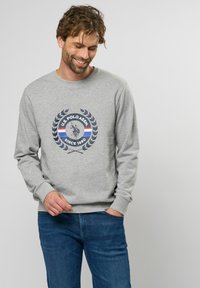 Grijze sweatshirt met een ronde halslijn, voorzien van een centrale marineblauwe graphic van een polo speler omringd door lauwerbladeren en kleurrijke strepen.