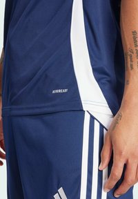 Marineblauw sportshirt met witte accenten en het "AEROREADY" logo. Heeft een zachte, vochtafvoerende stof en een gestroomlijnd ontwerp voor comfort.