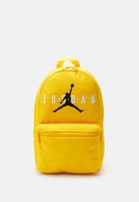 Zaino giallo realizzato in tessuto resistente, con tasca anteriore con zip, logo Jumpman nero e il testo "J O R D A N" sul davanti.