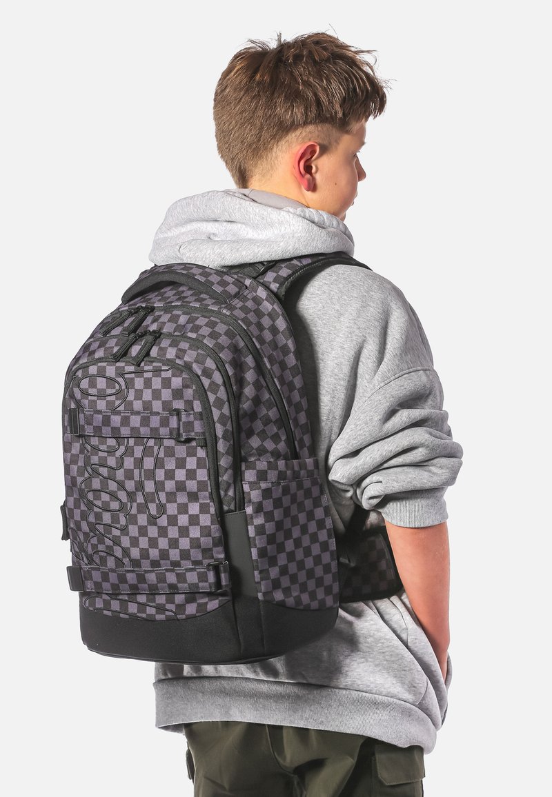 Černý a šedý kostičkovaný batoh s nastavitelnými popruhy a dvěma bočními kapsami. Má hladkou texturu a velké logo na zadní straně.