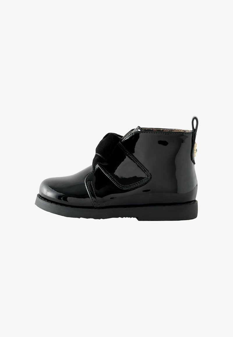 Schwarze Lackleder-Ankle Boots mit Klettverschluss, runder Zehenform, stabiler schwarzer Sohle und einer Zuglasche an der Rückseite für ein einfaches An- und Ausziehen.