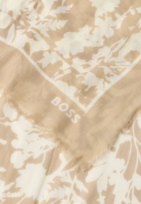 Béžový kvetinový šál s bielym vzorom, ošúchanými okrajmi a jemným textúrovaným povrchom. V rohu je značka "BOSS" v bielej farbe.