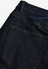 Donkerblauwe denim jeans met een achterzak met nette stiksels en een ceintuurlus op de taille, met een gladde, minimalistische textuur.