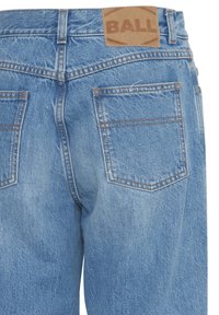 Gai zilu denim bikses ar augstu jostas vietu, ar brūnu ādas plāksni ar uzrakstu "BALL" un divām aizmugurējām kabatām ar oranžiem šuvumiem.